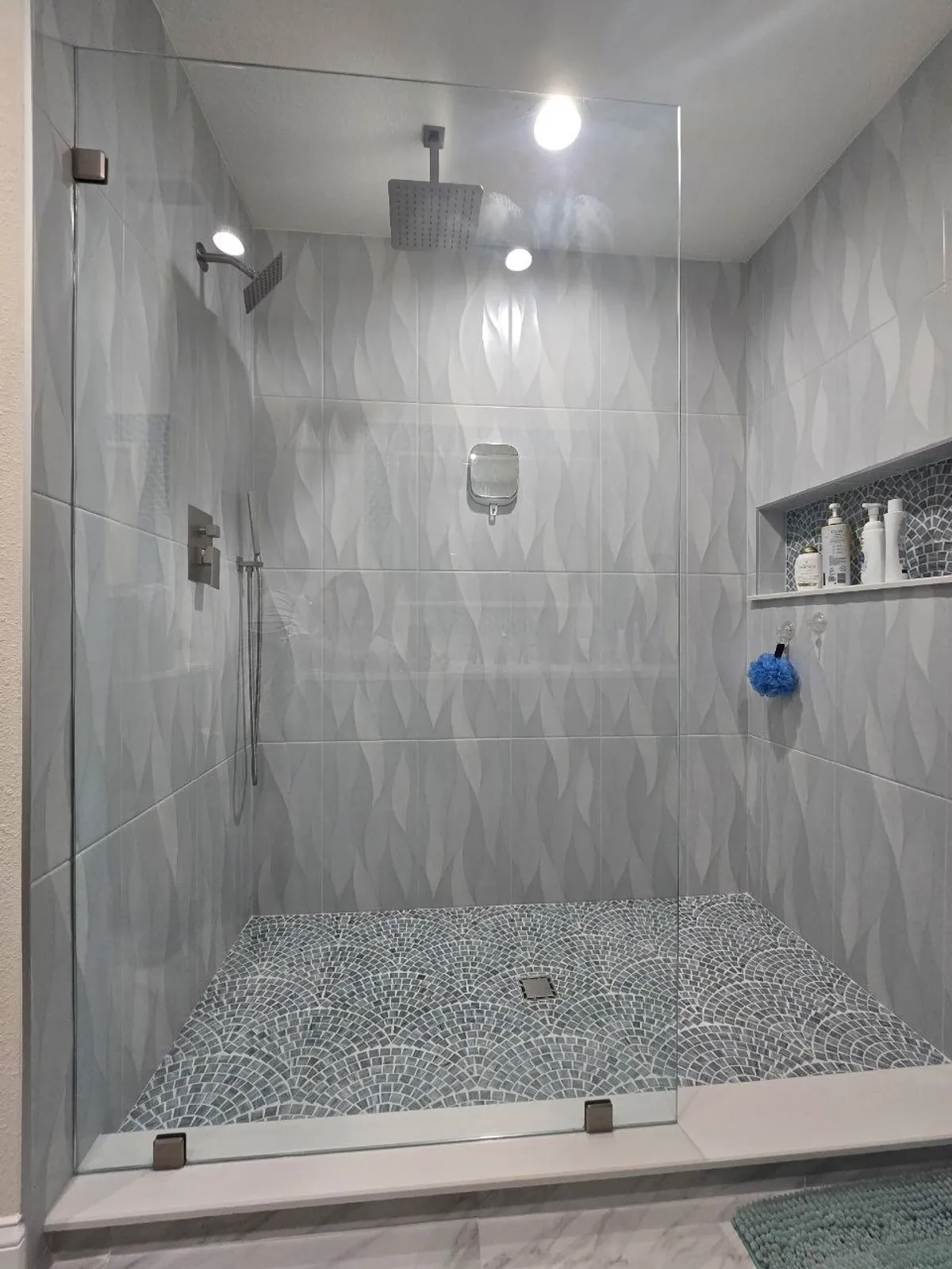 Textured feather-pattern tile shower with rain head and pebble-mosaic pan