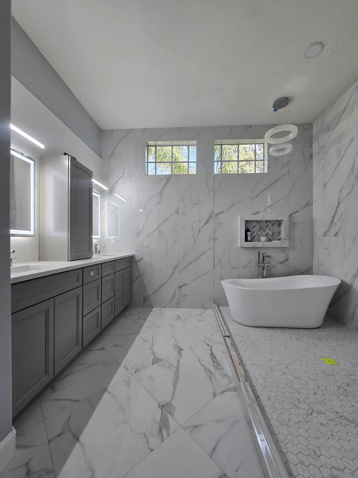 Calacatta marble master bath with freestanding tub and gray shaker vanity